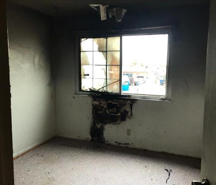 Room with a window, white walls, and black soot stains. 