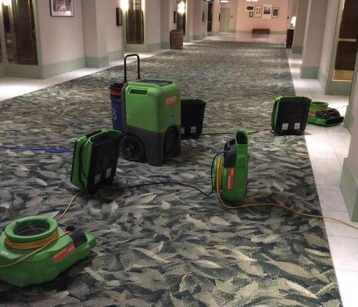 Drying equipment (dehumidifier and air movers) placed on the hallway of a building