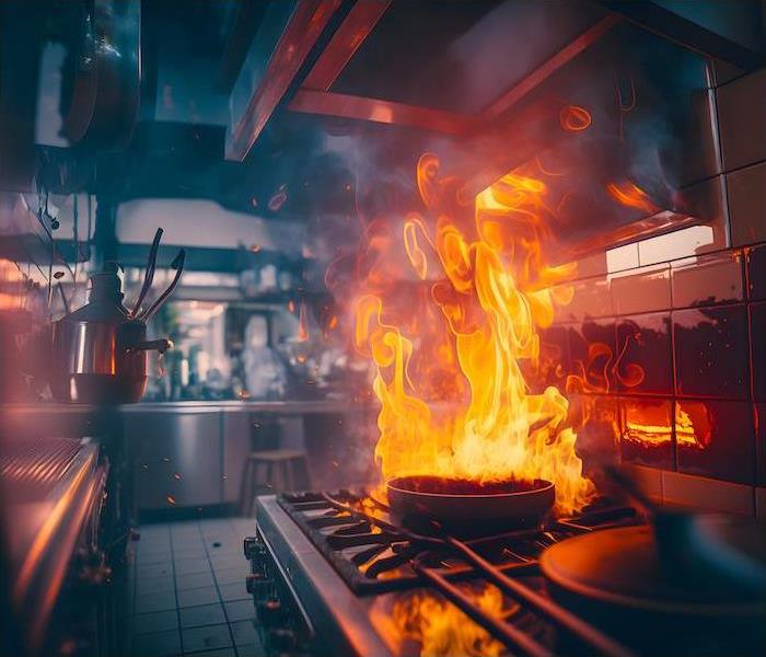 Dramatic image of a commercial kitchen with the gas stove ablaze in a grease fire around the pan