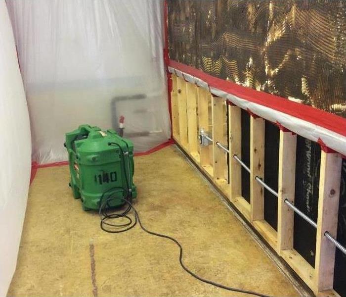Drywall removed, air scrubber placed on floor, containment barriers placed on wall